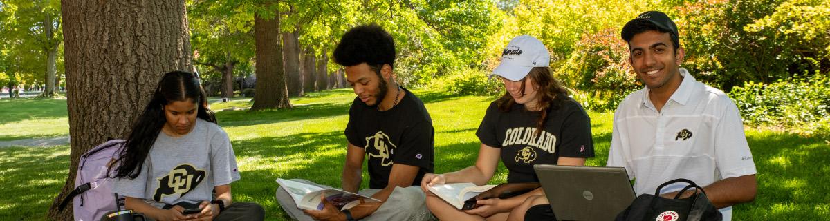 Students outside reading books and a computer