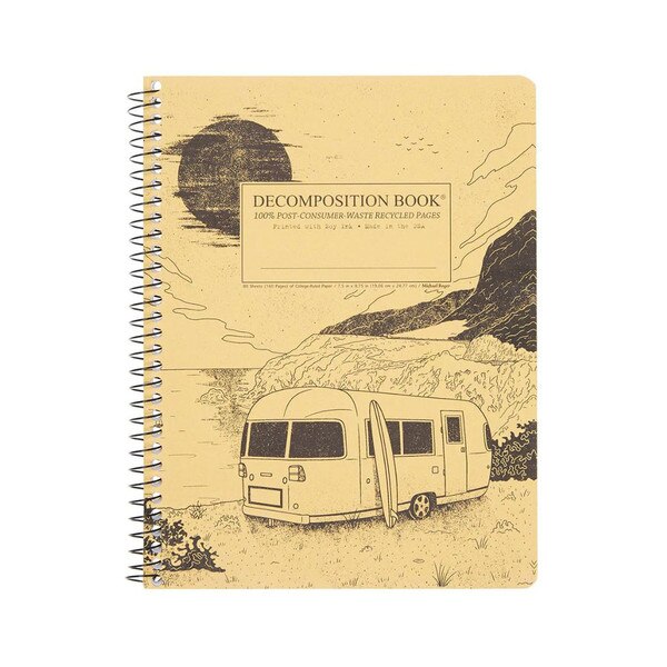 This is a Decomposition branded spiral bound composition book. The text on the cover is black. The cover is yellow and illustrates the Big Sur landscape. There's a trailer and a surfboard pictured.