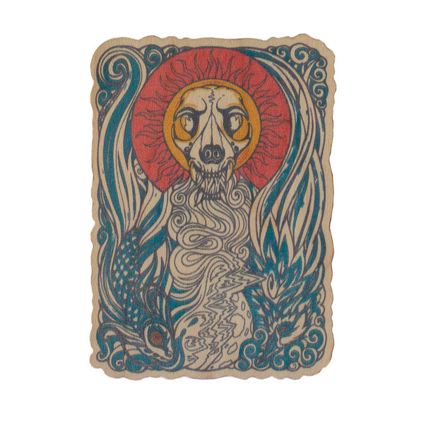 A printed wooden sticker with a skull and sun, and intricate details in red, orange, and blue.