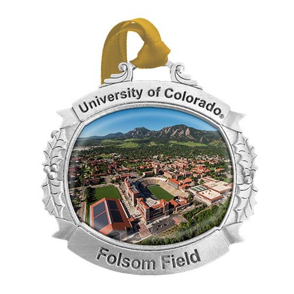 A metal ornament with a picture of Folsom Field, with University of Colorado and Folsom Field in engraved lettering, tied with a Vegas Gold ribbon for hanging.