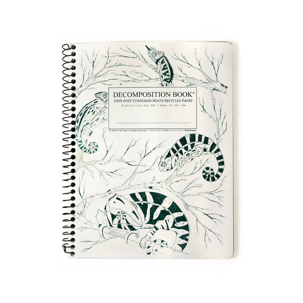 This is a Decomposition branded spiral bound composition book. The text on the cover is dark green. The background is white with four dark green chameleons sitting across the cover on branches.