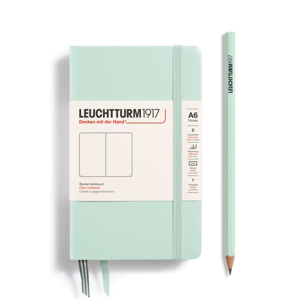 This is a small, mint green notebook with an elastic and two bookmarks. The pages are blank other than page numbers in the bottom corners.